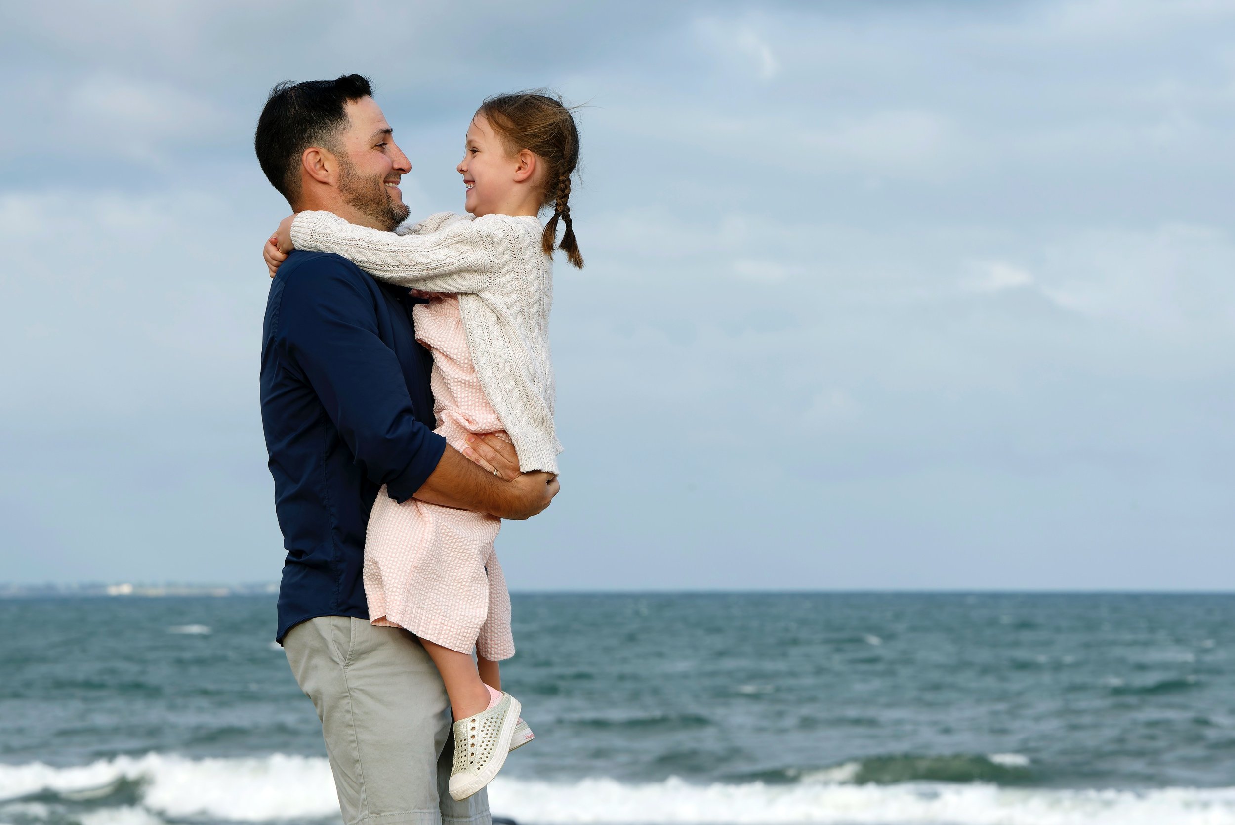 Father holding his youngest daughter on the shoreline.