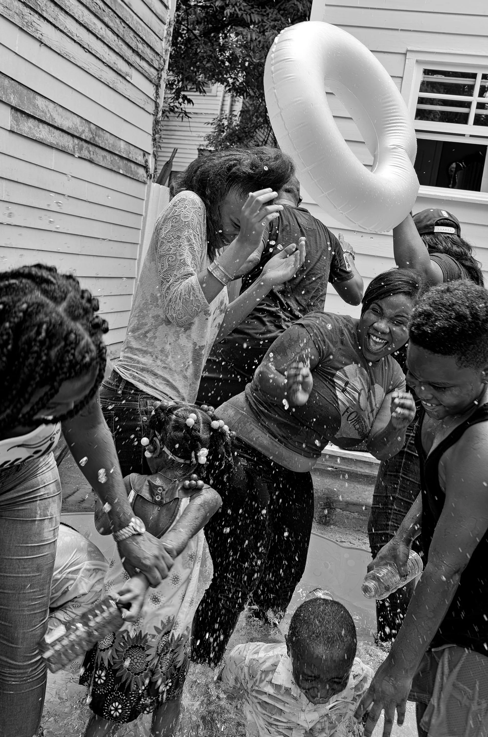 Family and children splash each other in a children's pool following a ribbon cutting for the St. Bernard Project.