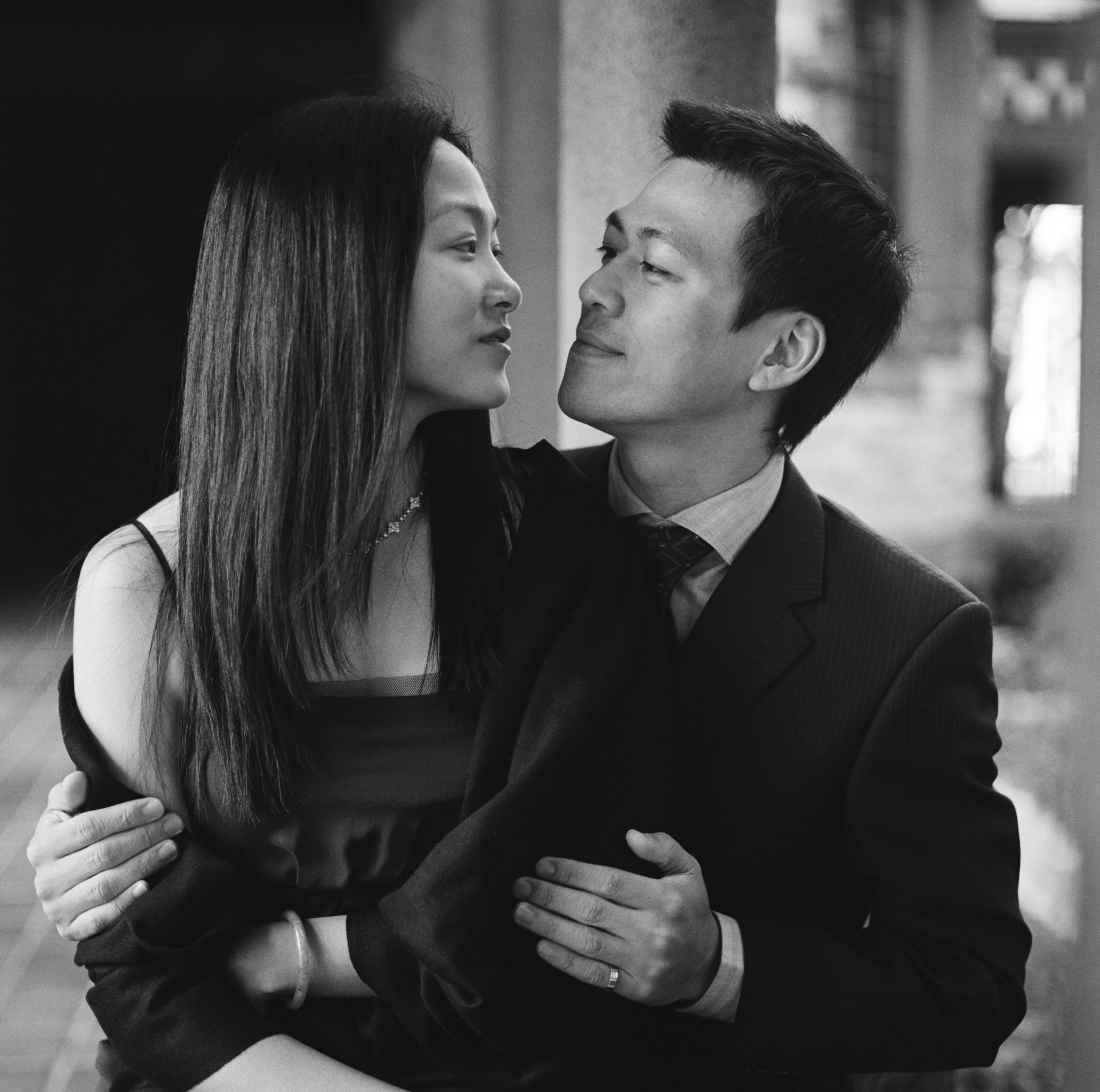 A black and white photo of a couple embracing and looking into each other's eyes, with the woman's face close to the man's face and their hands gently placed on each other's backs. Boston, MA.