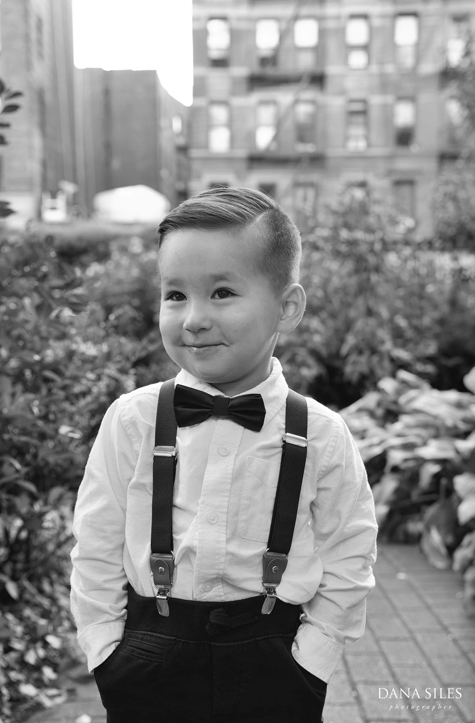 Adorable ring bearer wearing bow tie and suspenders before Jefferson Market Garden wedding.