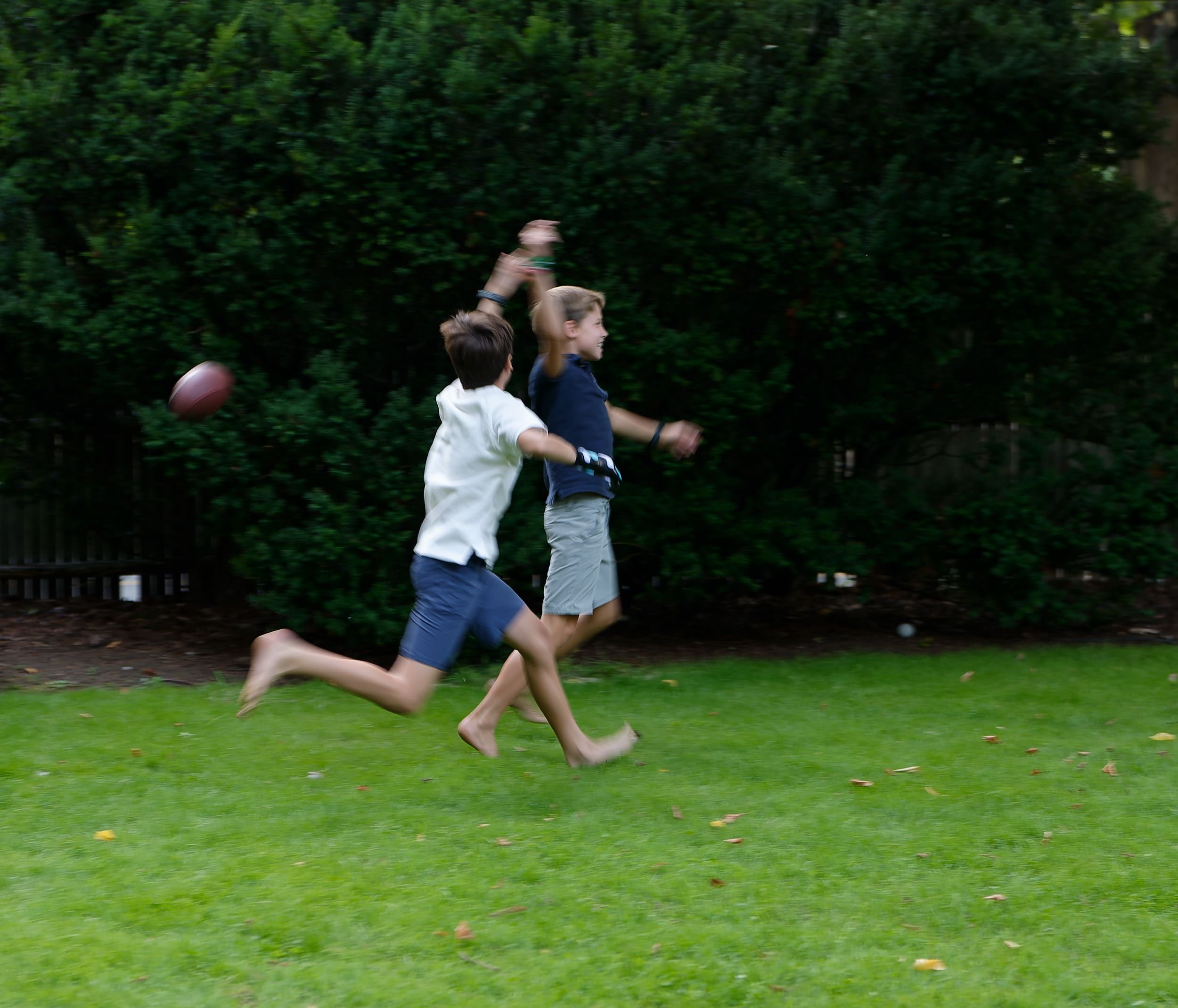 Two brothers runninng together outdoors at the family home.