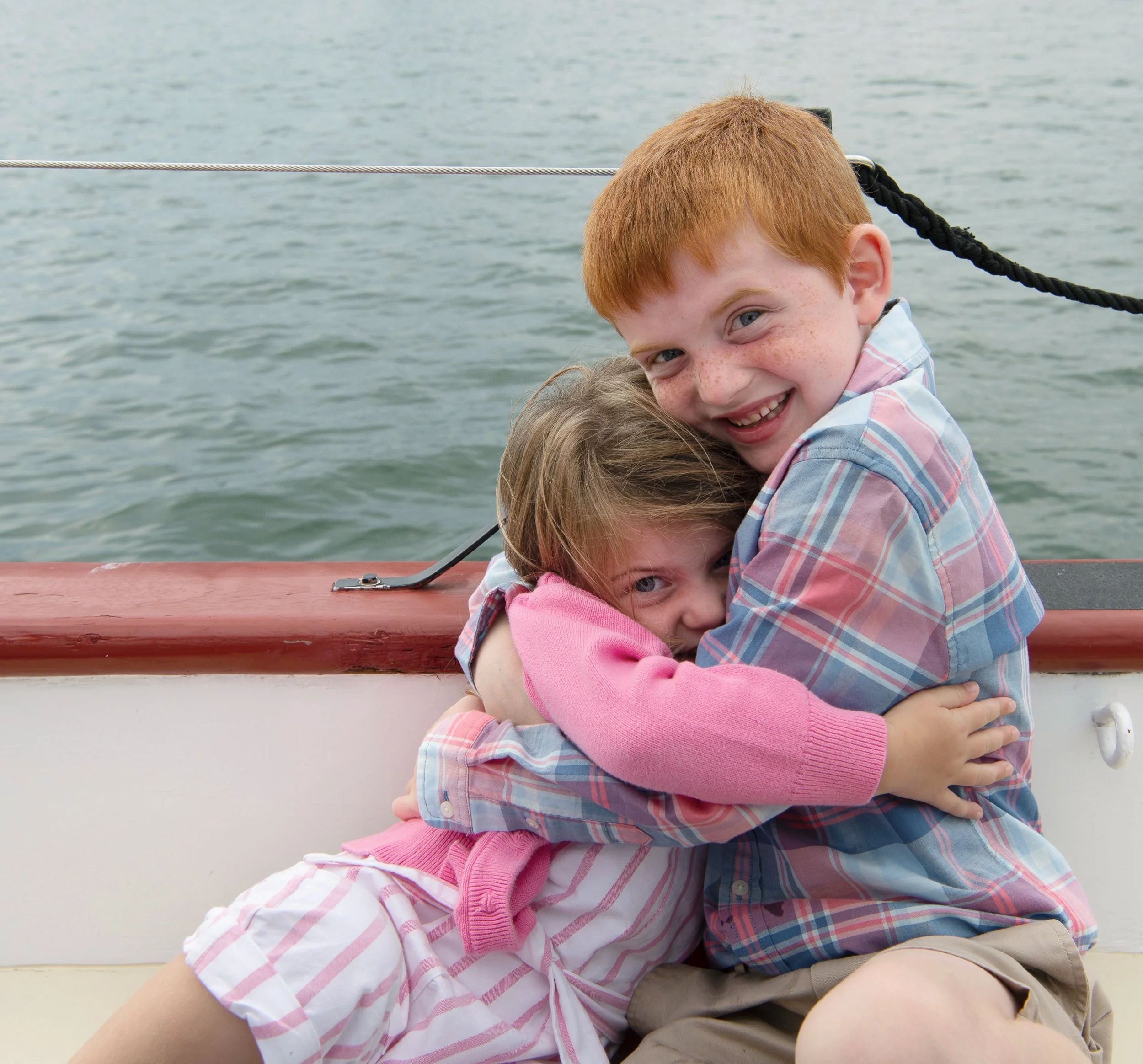 Two children hugging aboard Schooner Aurora during the harbor cruise
