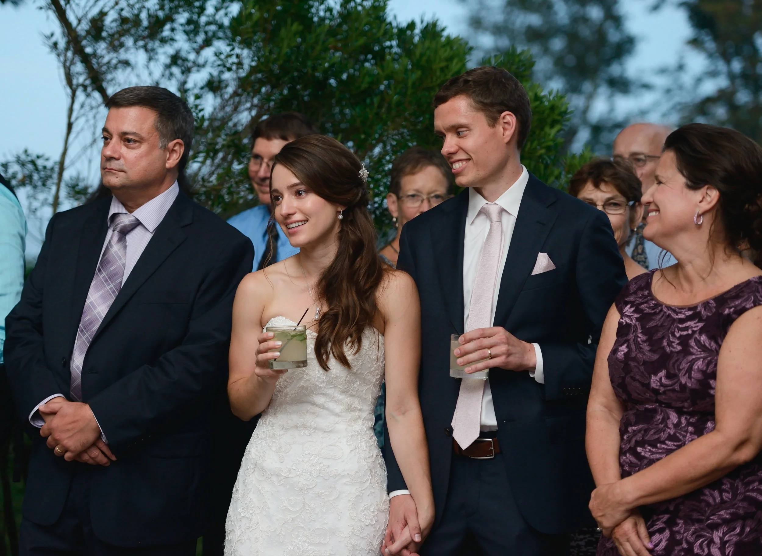 Bride and groom with family listening to speeches during outdoor Eolia Mansion reception 