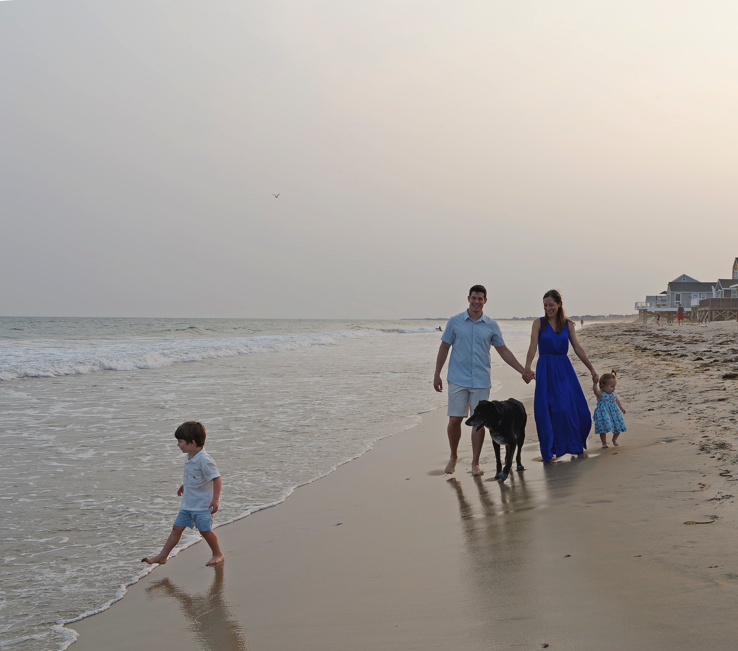 Family and dog walking along the Rhode Island shoreline