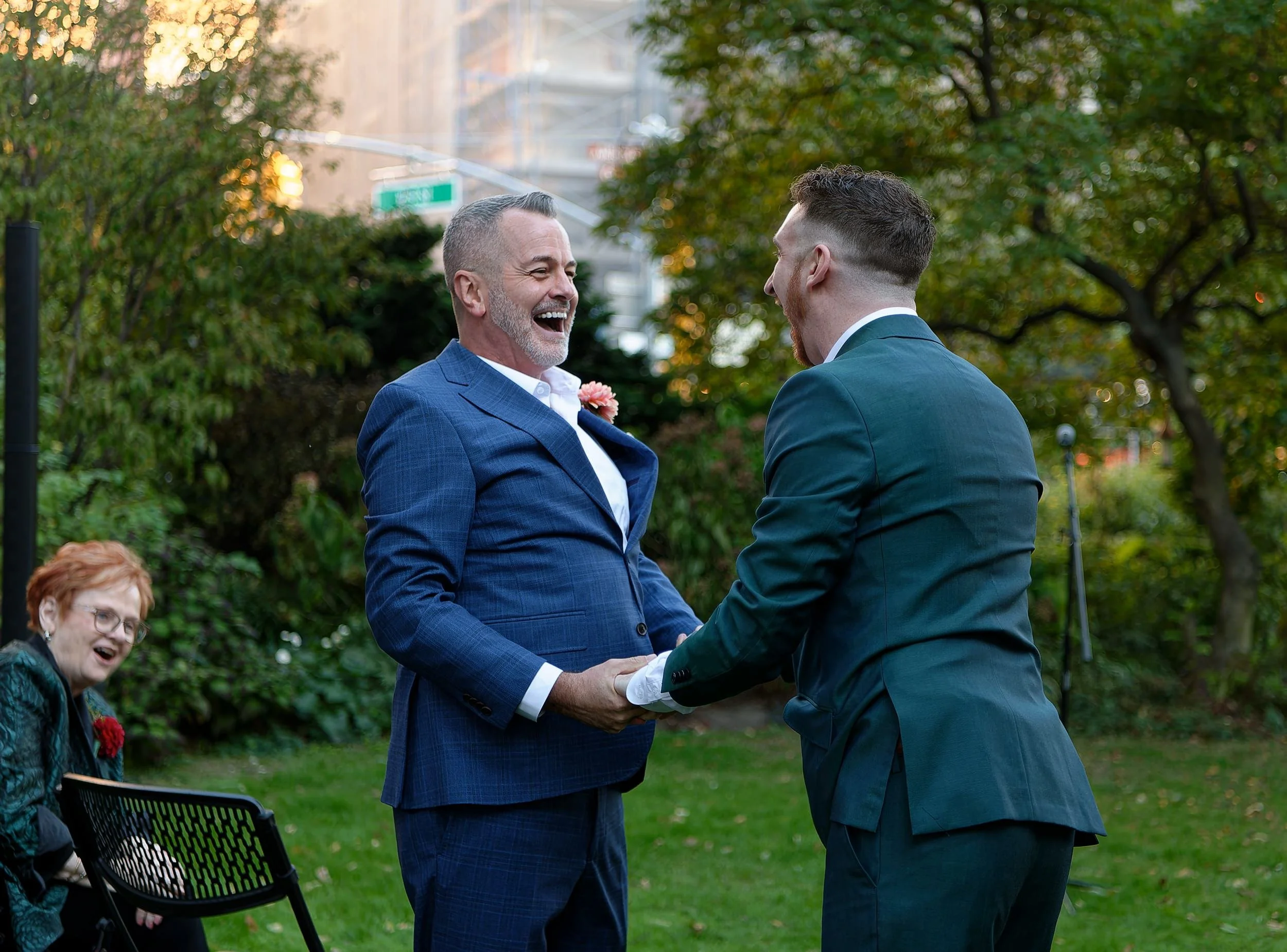 Elated grooms laughing and jumping after wedding ceremony at Jefferson Market Garden in New York City