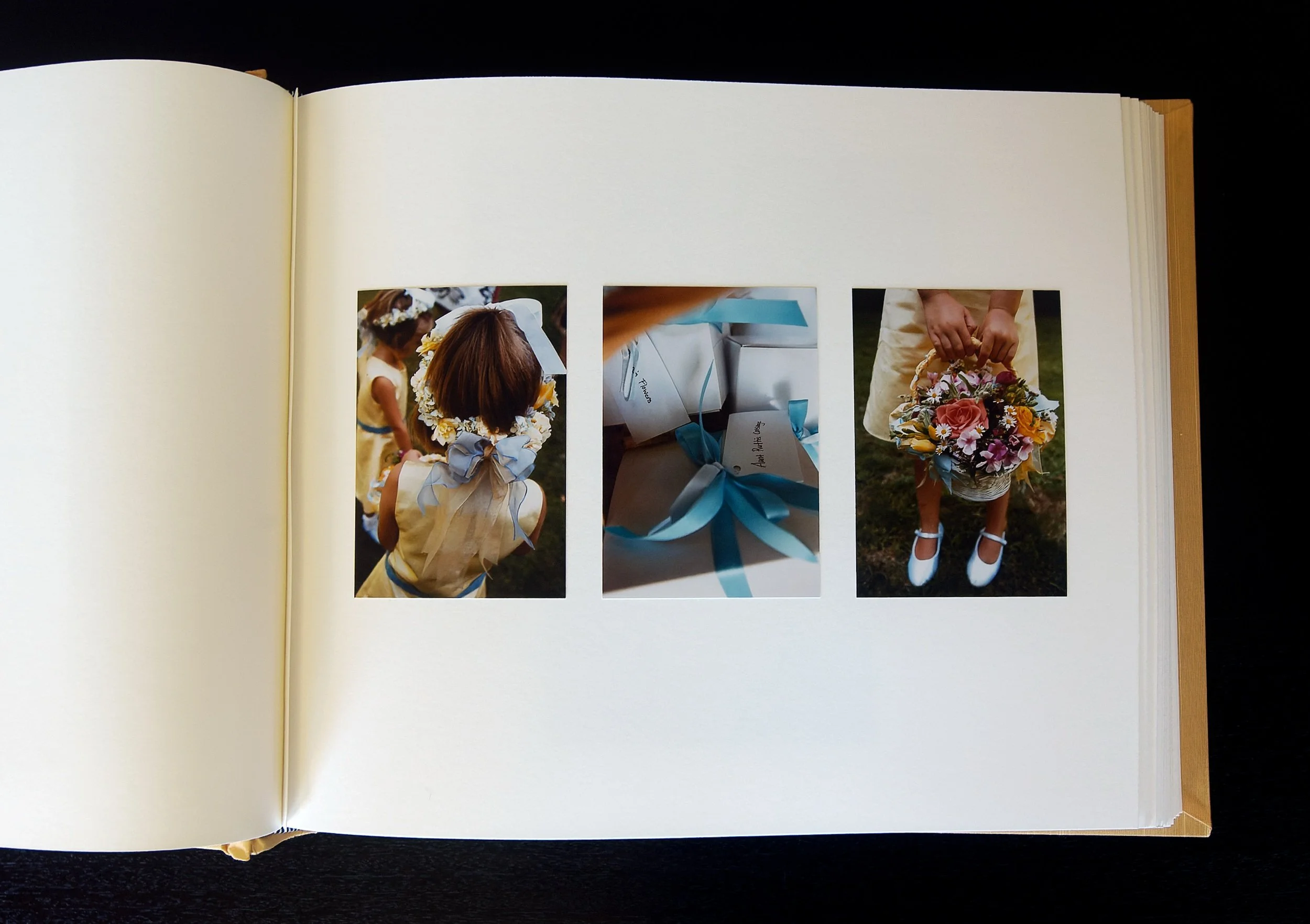 Open album with three vertical wedding photographs printed on pearl surface paper, hand-mounted.