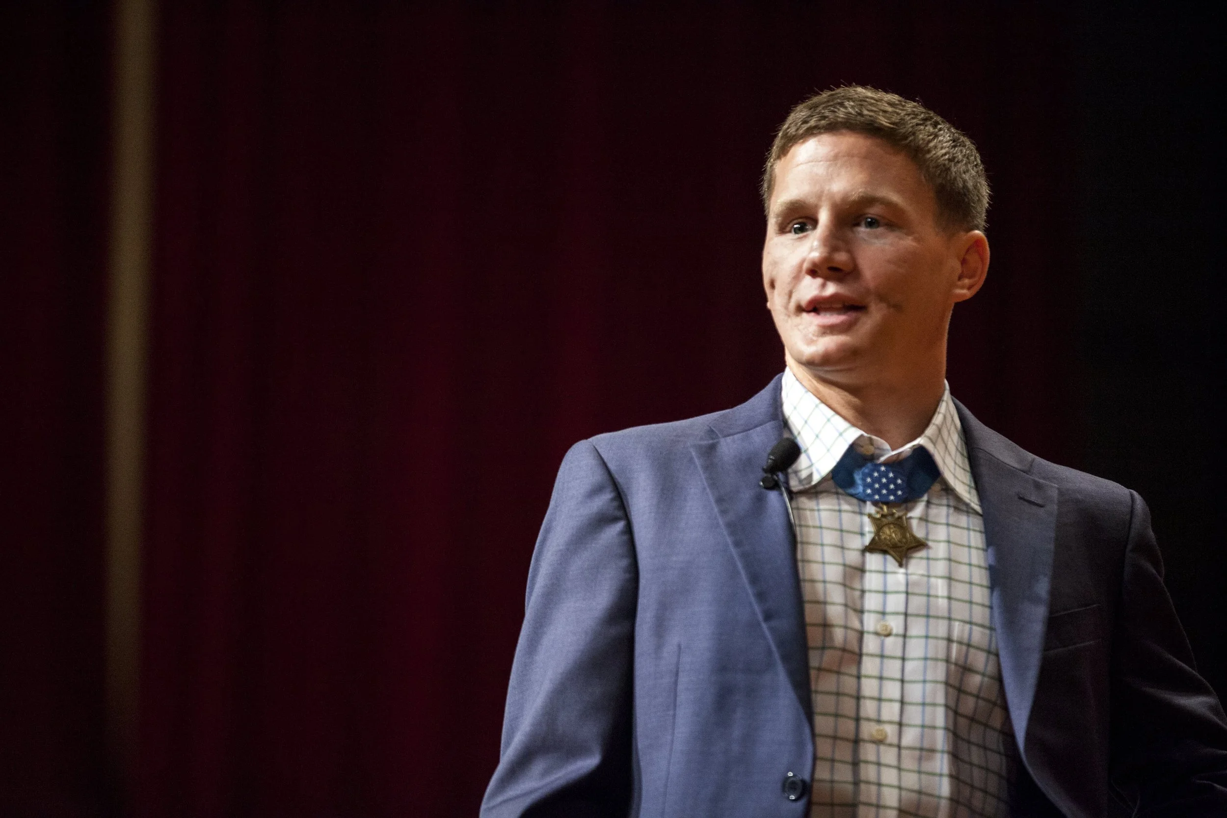 Portrait of Medal of Honor recipient Kyle Carpenter speaking from a stage to an audience