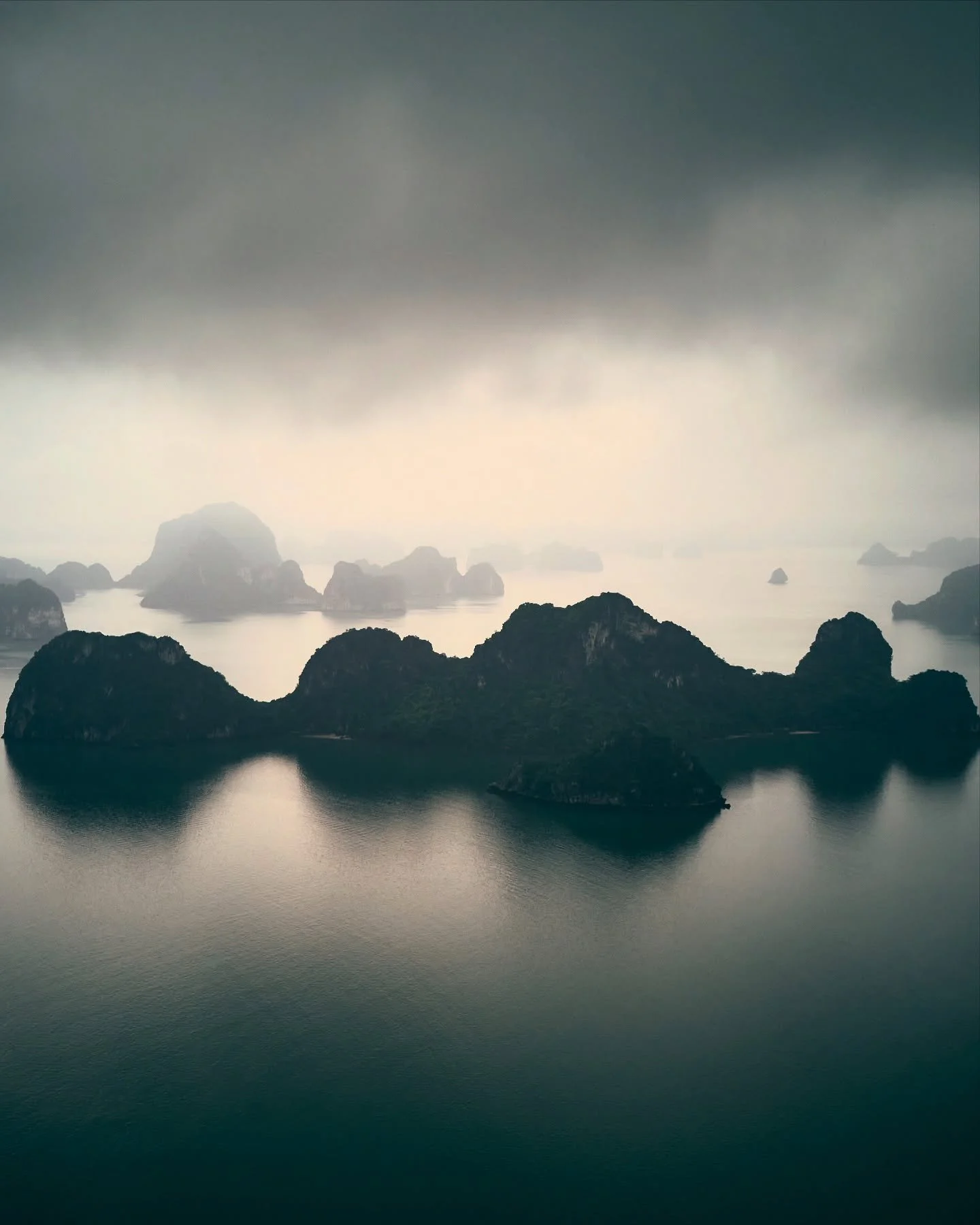 Veiled in mist and myth, the limestone giants of Hạ Long Bay rise like sleeping dragons from the sea. Their silhouettes drift in and out of view as clouds cling to the karsts—each one a silent witness to eons of geologic transformation and lege