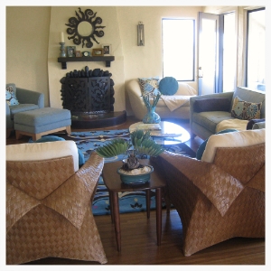 Spanish revival living room with eclectic and natural touches in wicker, rusty metals, silk and wool. Large room is made cozy by furniture placement that surrounds the charming vintage fireplace.