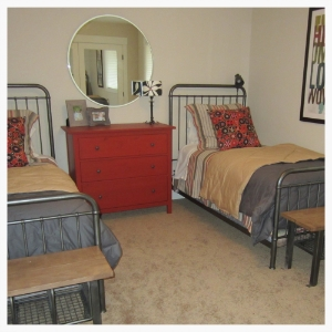 Boys' bedroom includes matching twin beds covered with steel gray and a hint of bright color. Reclaimed wood foot benches are resting spots for shoes, Nerf Guns, and a variety of other inevitable floor clutter.