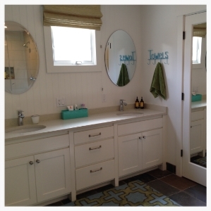 Guest bathroom gets a modest renovation with non-custom-made cabinets. Inexpensive mirrors are from a local hardware store. Slate floors are skid-proof for wet feet coming in from the outside pool area.