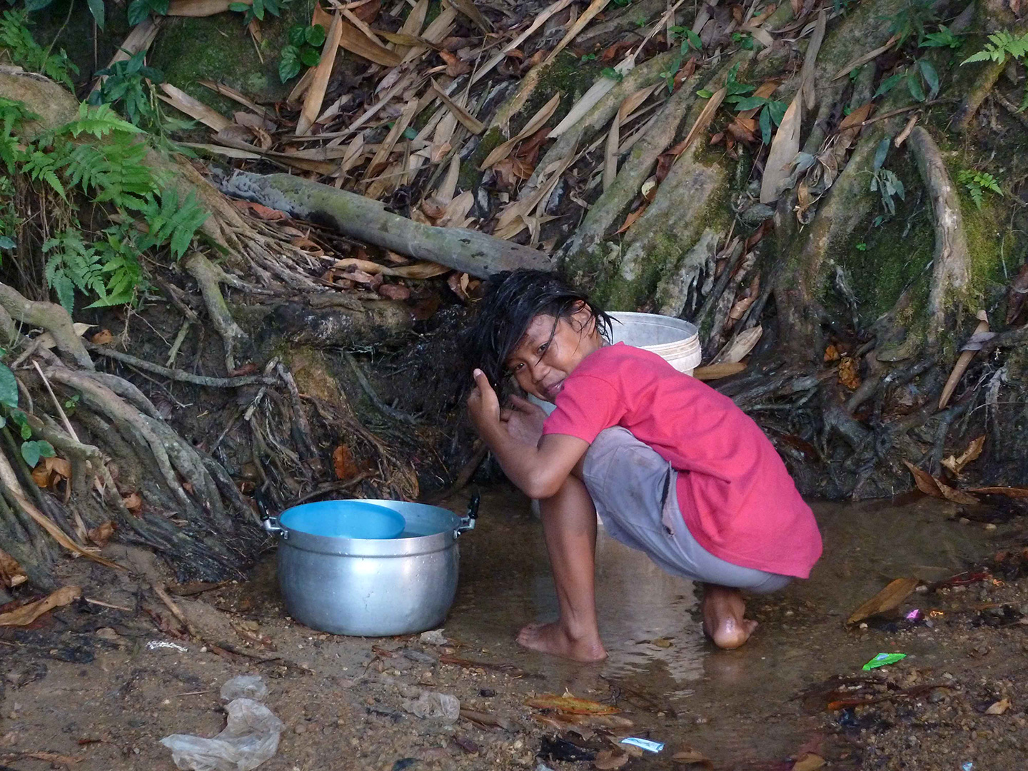 A child collecting water and washing her hair (Fung Na community)