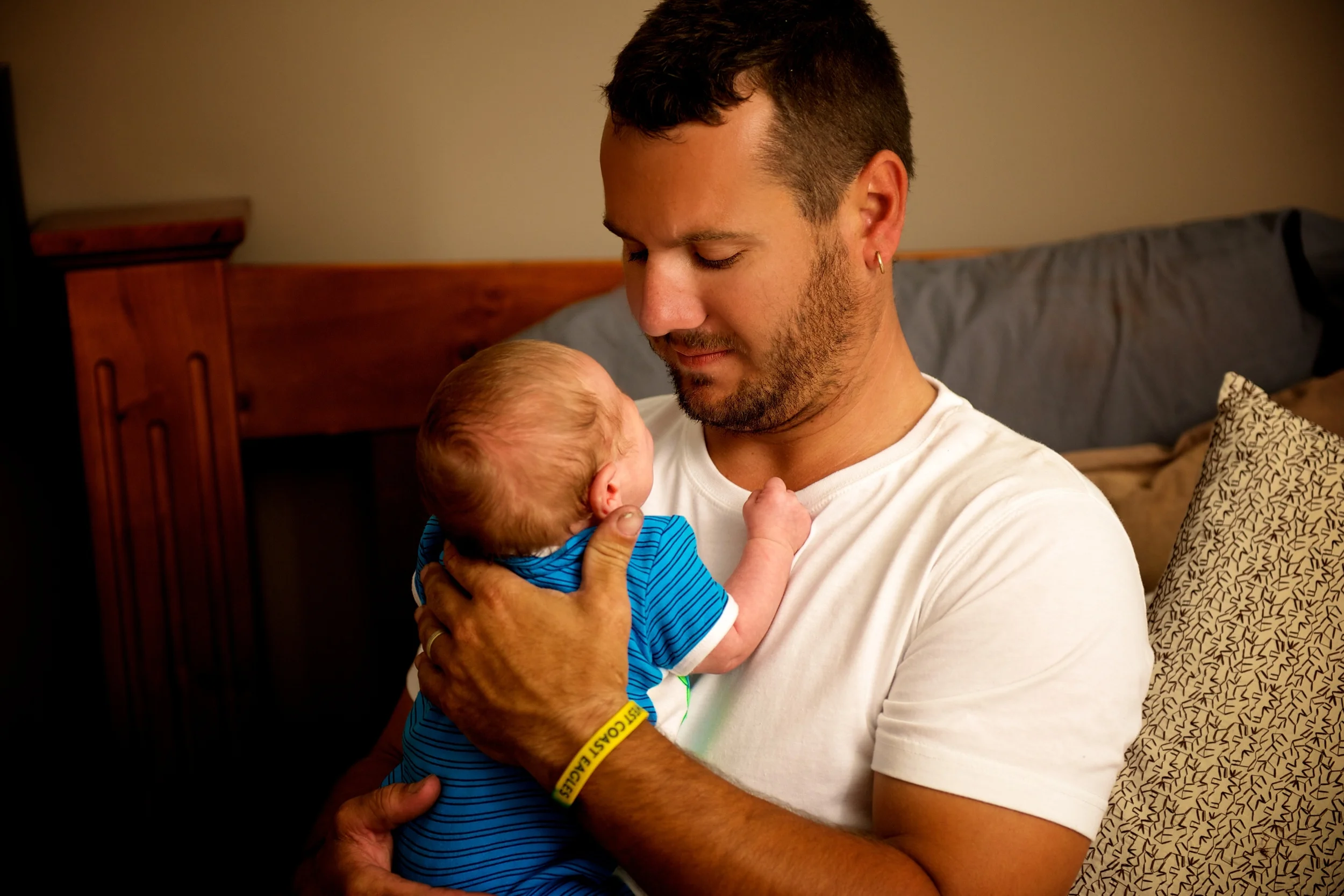A dads tenderly holds his new baby boy. Image Taken by Warnock Imagery