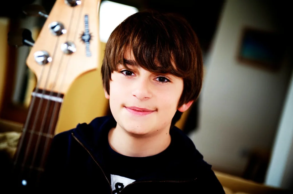 A great family photographer will try to capture everyones personality. In this photograph by Warnock Imagery a boy holds his guitar