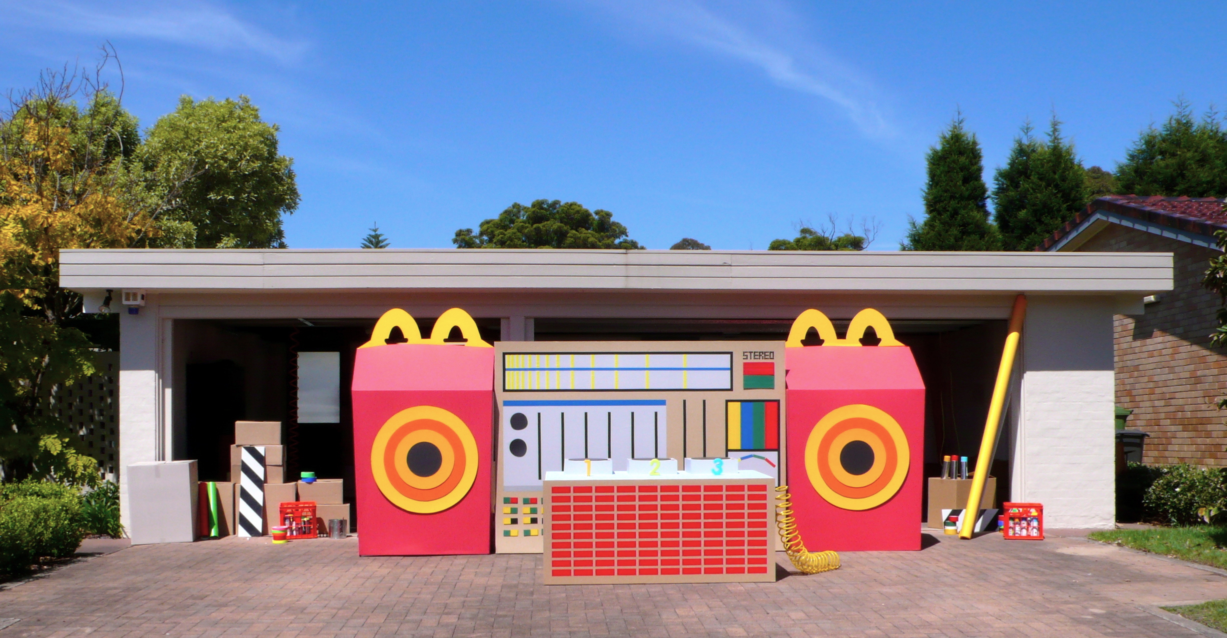 giant oversized stereo constructed out of cardboard & coloured gaffa tape with giant happy meal as speaker 
