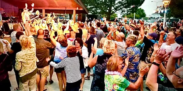 Air Margaritaville plays for a concert of hundreds of people at an outdoor concert venue.