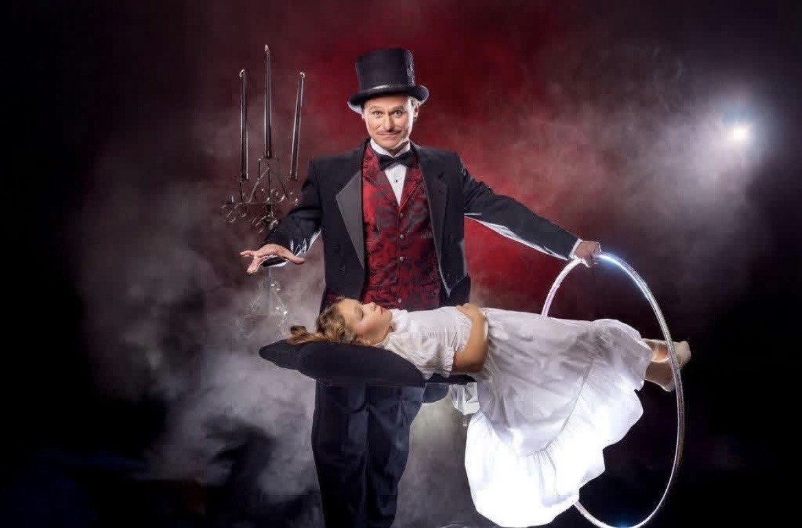 A photo of Elton the magician making his daughter levitate through a ring.