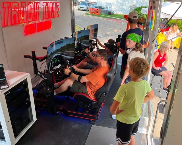 A group of kids sit in giant chairs at the Sim Racing station.