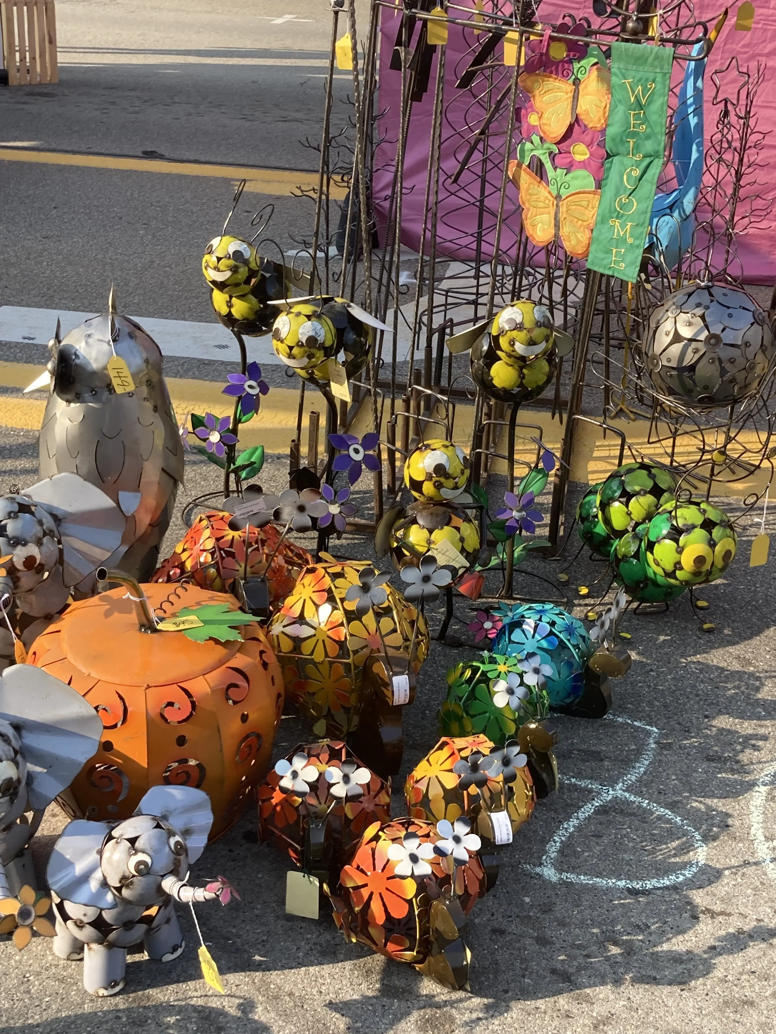 A variety of colorful metal sculptures surround a vendor booth at the Howell Melon Festival.