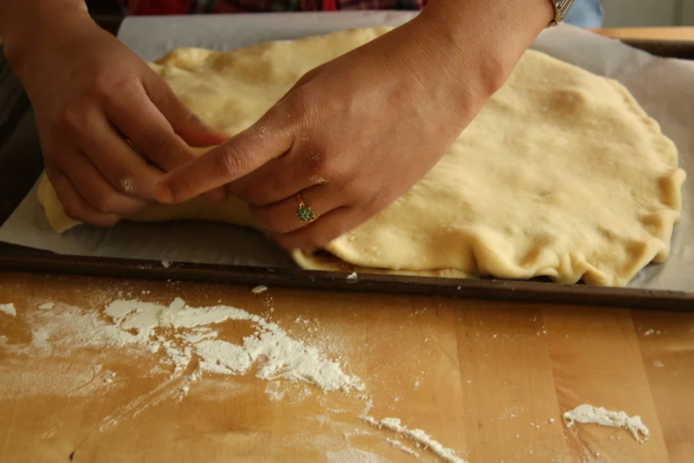  Pinching the dough down around the filling. A tight seal is important to avoid having your filling leak out during cooking. 