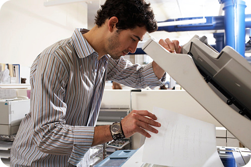 Man leaning placing a sheet a paper over the copy machine.
