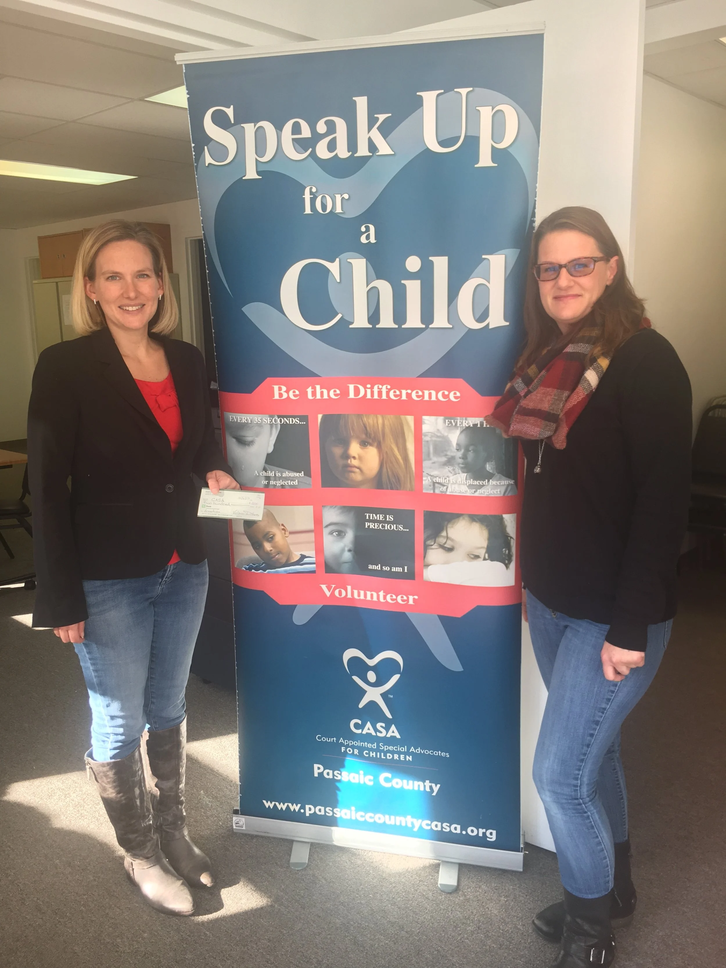 CASA Executive Director Erica Fischer-Kaslander accepts a donation from Katie Scheidt of the Mom's Club of Wayne