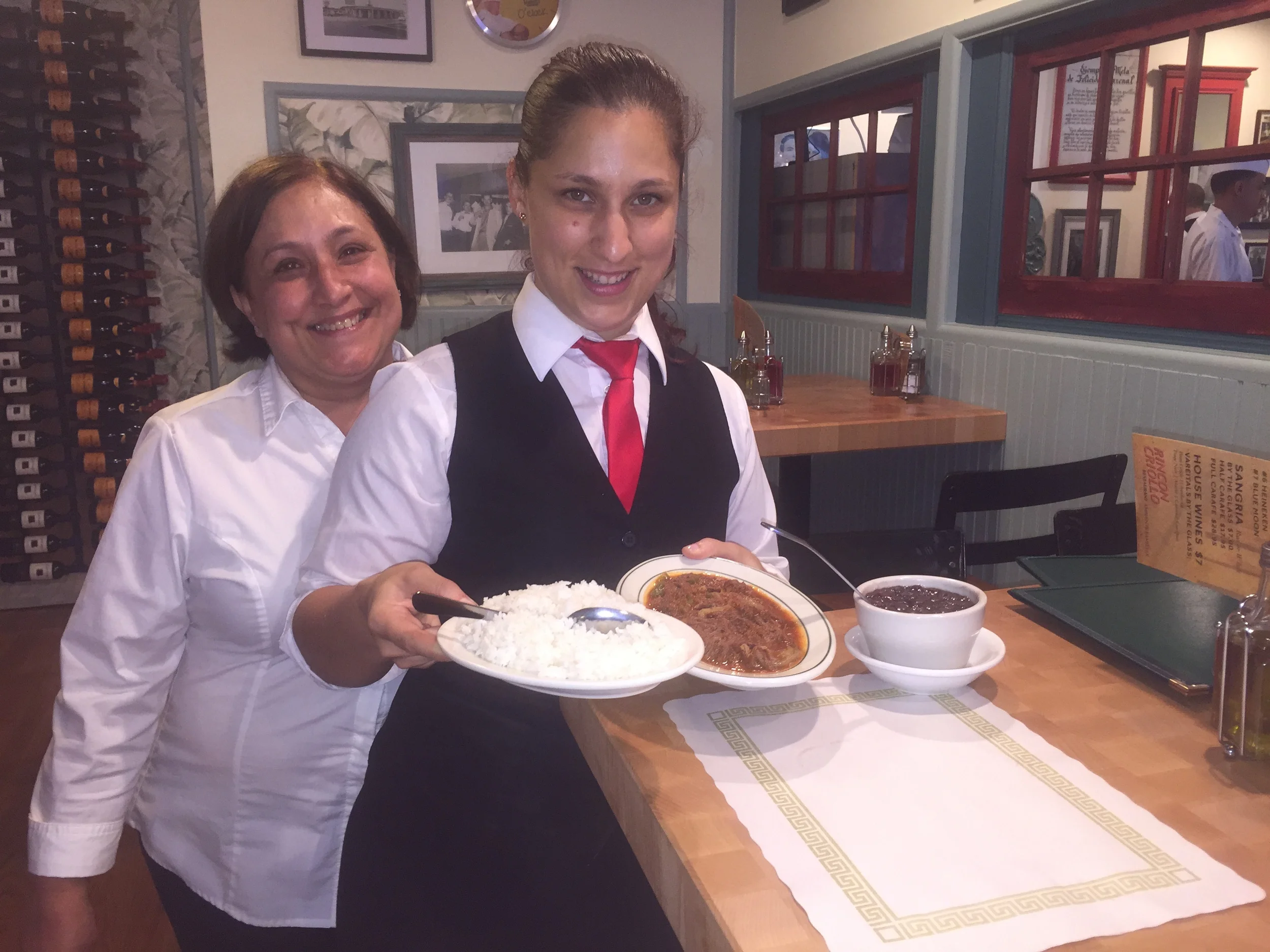 Manager Esther Acosta, second from left, and her mother, Gilda Acosta, display the restaurant’s signature dish, ropa vieja.