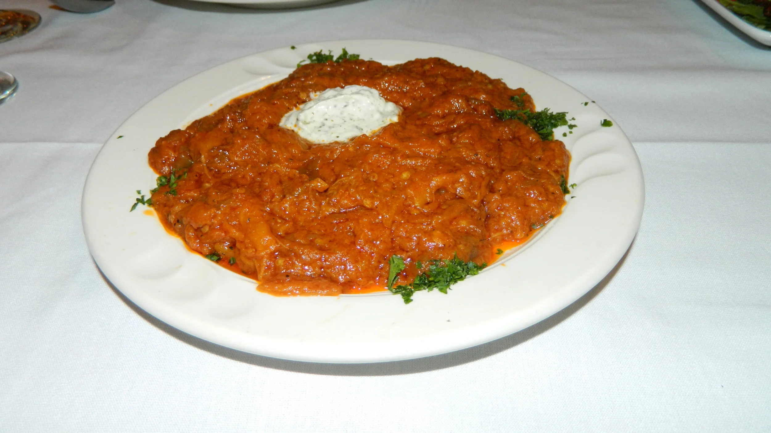 The kashk bademjan consists of cooked eggplant in tomato sauce topped with yogurt.