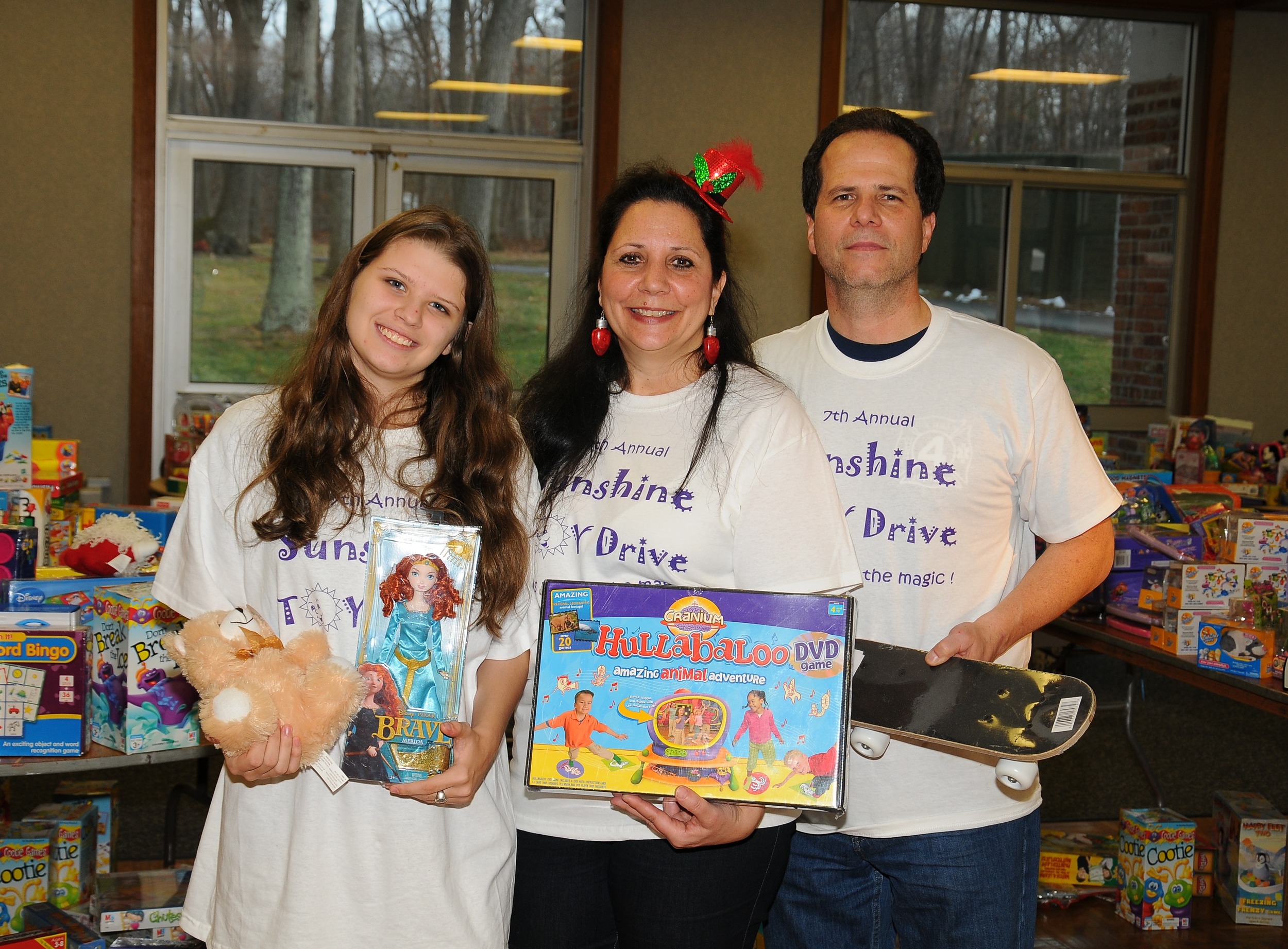 The Plumitallo family stands among the many toys donated to their 7th annual Sunshine Toy Drive while at the Dix Hills Fire Department Headquarters. Pictured from left are Victoria (Sunshine), Hope and Mike Plumitallo.
