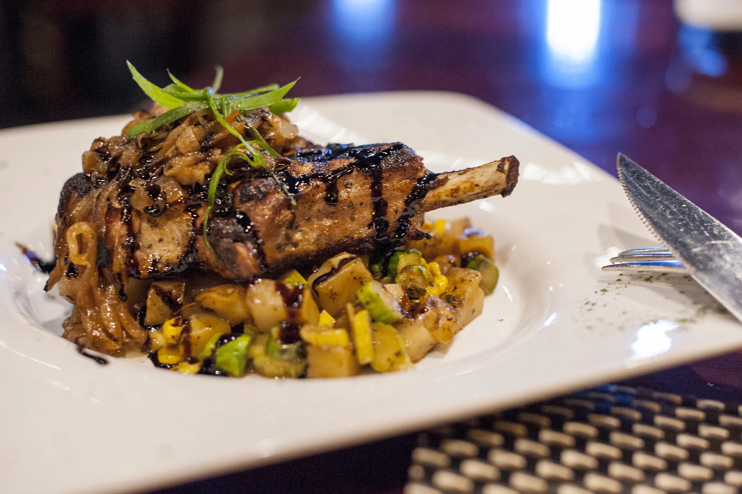  The Pork Chop special plates a rich pork chop, Yukon potato, asparagus, corn fricassee, caramelized onion, with a drizzle of balsamic glaze as a delightful balance of sweet and savory tones. 