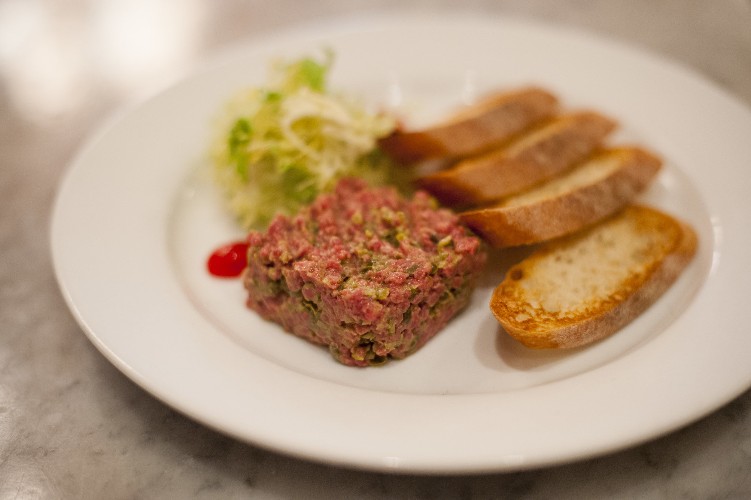  Steak Tartare brings together succulent raw beef mixed with capers, dijon mustard with toasted baguette slices and frisee salad. 
