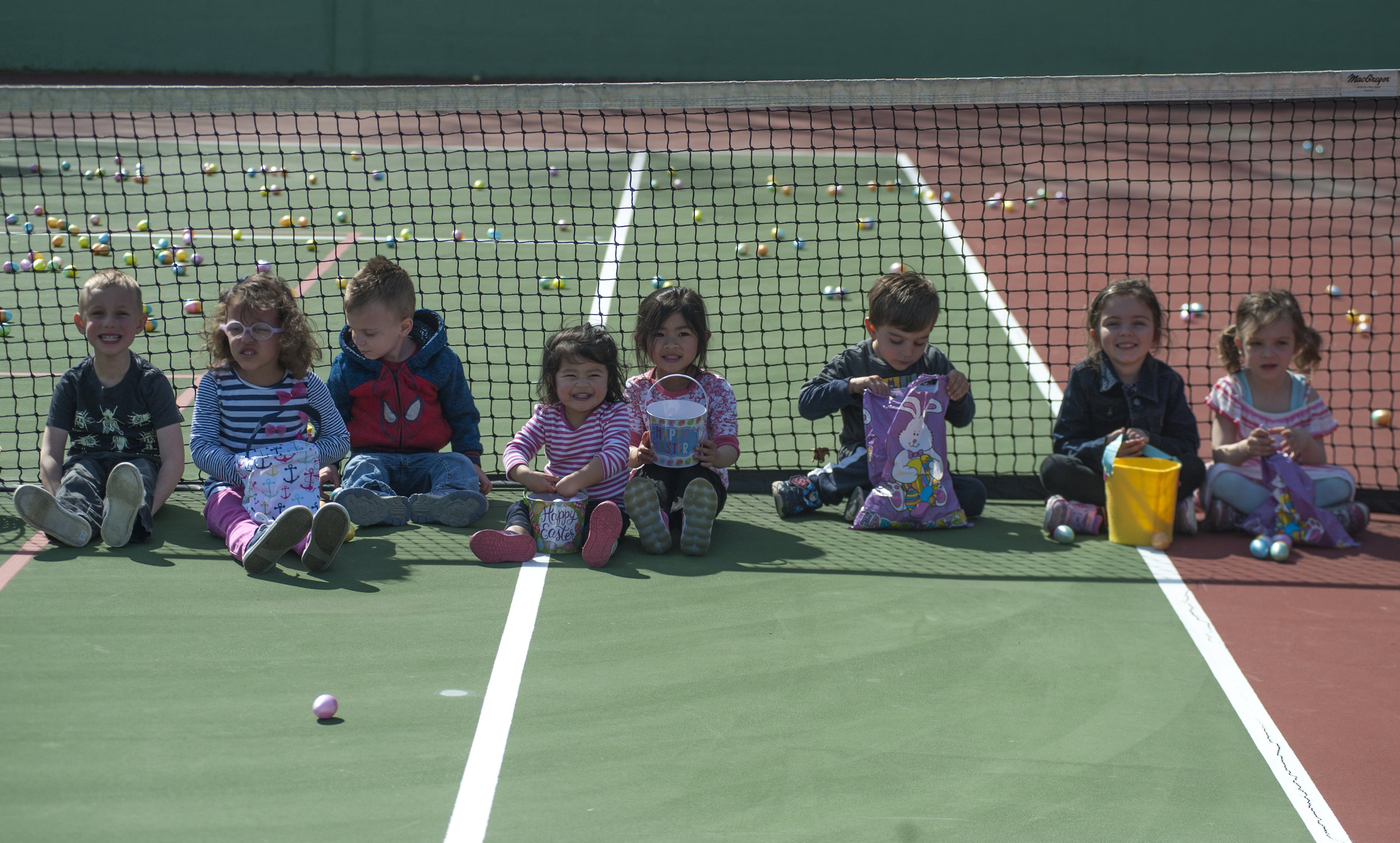   Long Islander Photos/David Weber  Three areas were available for children to collect eggs from at ‘Eggstravaganza,’ each for a designated age group. Children 5-8 years old sit on the tennis courts in Heckscher Park for a photo. 