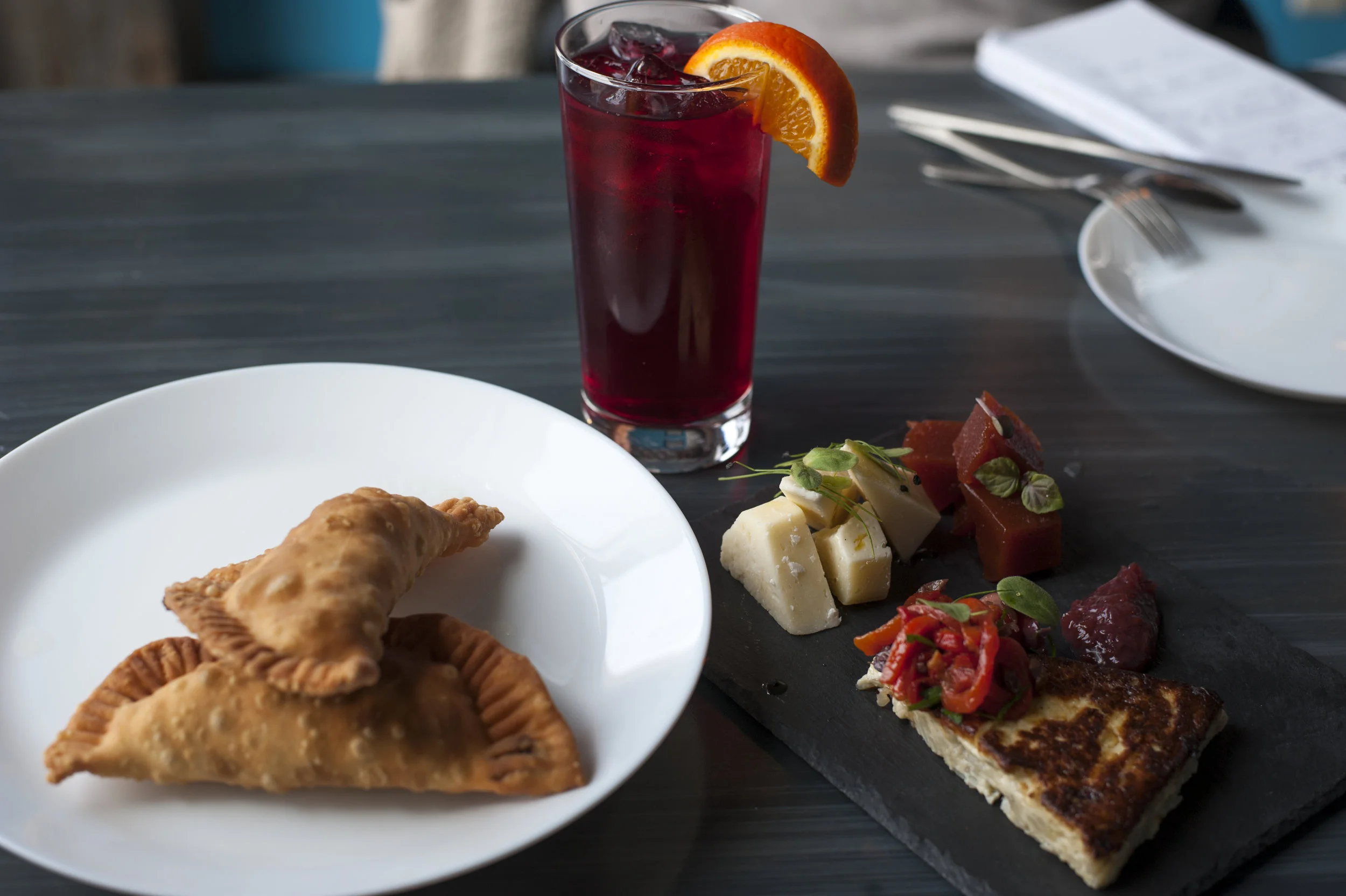  Classic baked Empanadas are shown with the Guava Plate, a medley of sweet and savory sensations, alongside a non-alcoholic refreshing sangria. 