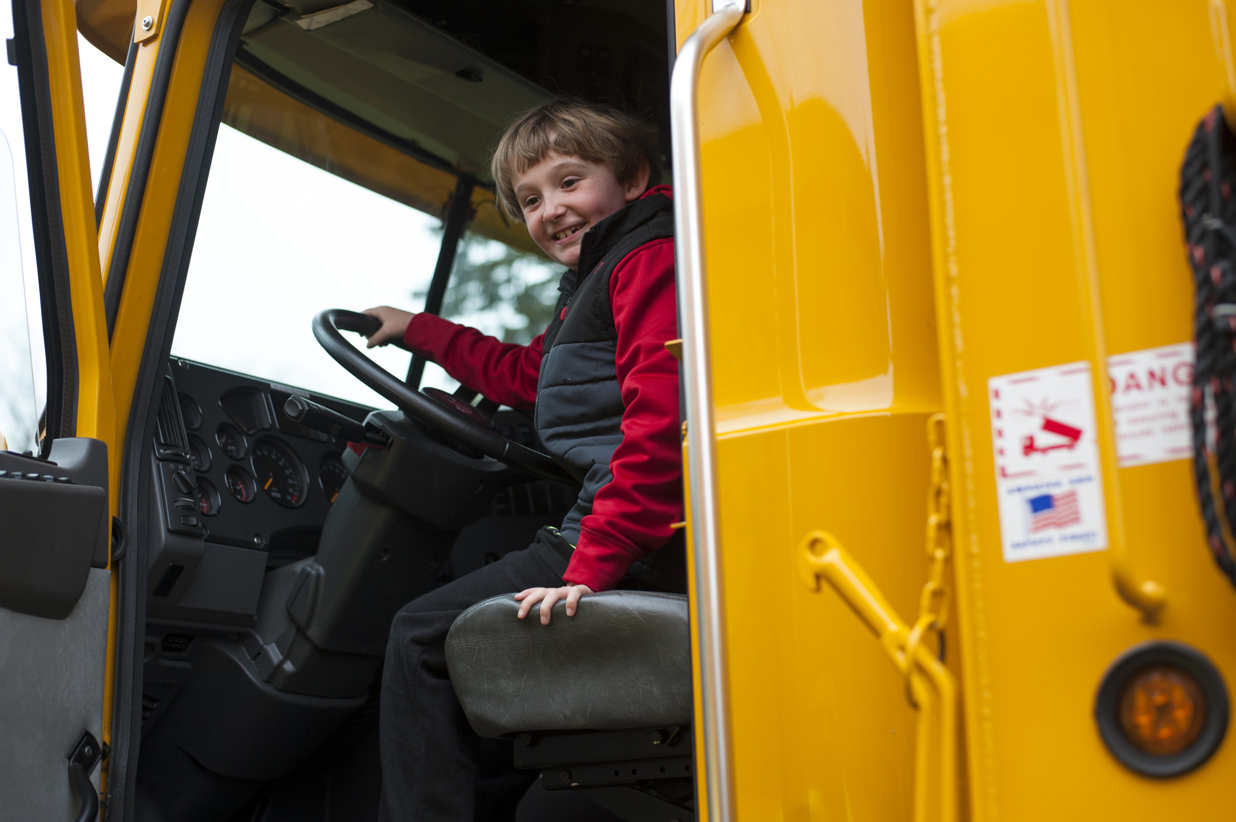  Ryan Chapman honks the horn of a Mack dump truck as his parents try persuading him to let the next child have a turn. For a brief moment, kids had an opportunity to sit in the driver’s seat of several work vehicles, including two NYPD police cars, a