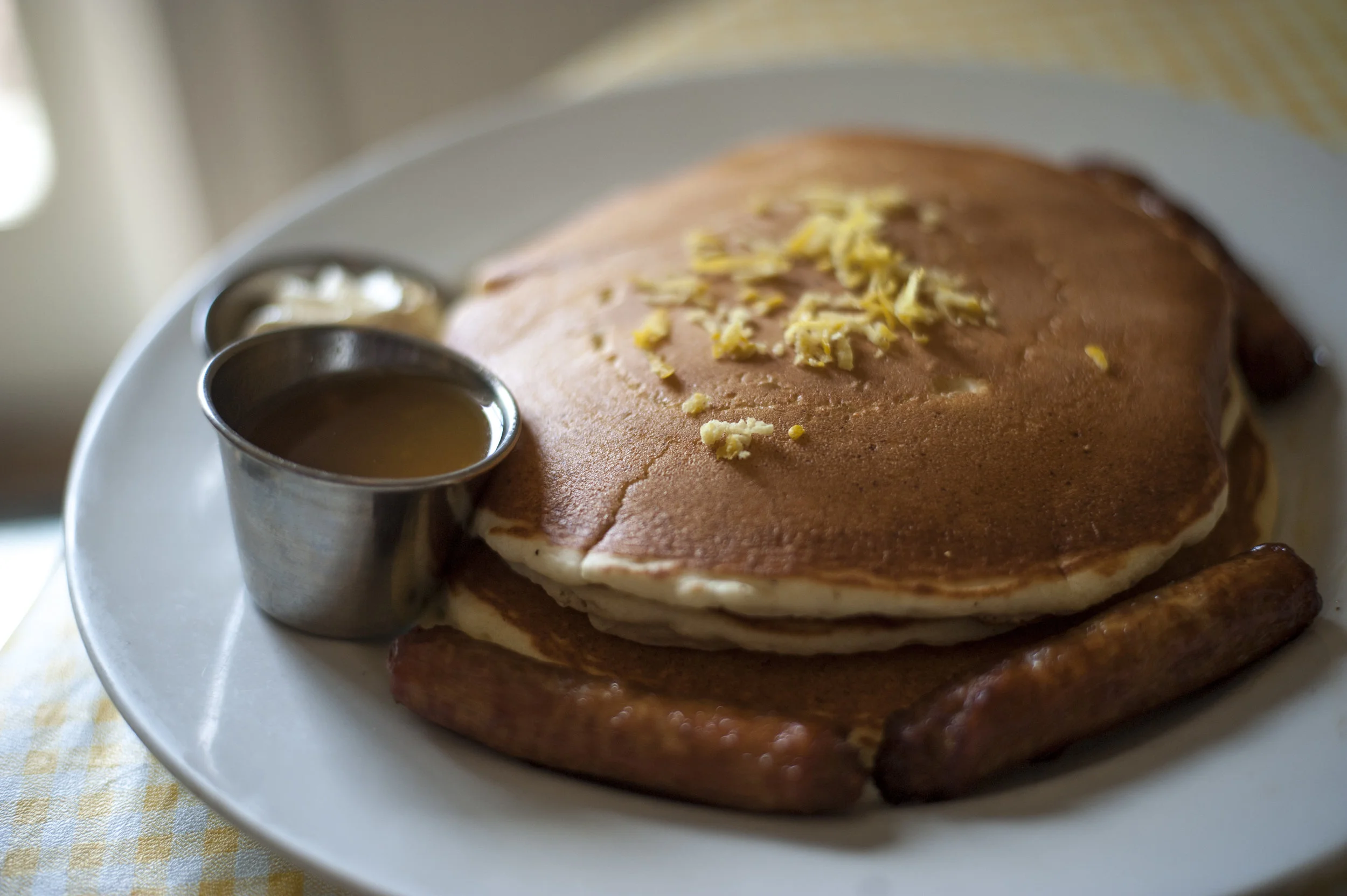  As a fluffy, creamy treat, the Ricotta &amp; Lemon Zest Pancakes offer up a full stack with lemon zest and a side of homemade honey citrus maple syrup and served with a choice of bacon, sausage or ham. 