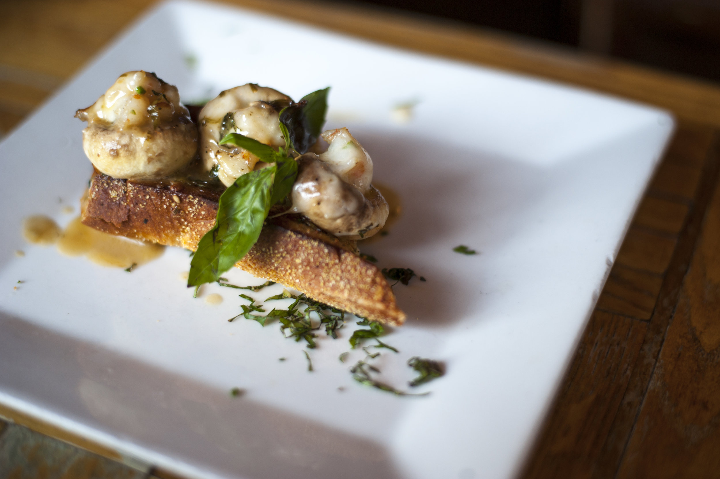  The Shrimp Cargot is drizzled with garlic lemon sauce, serving up deliciously savory shrimp stuffed into a mushroom, atop a country bread crostini. 