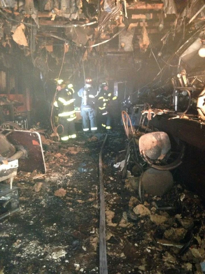   Photo by Chris Ciaci   Firefighters work on the charred inside of Gunther’s Tap Room. 