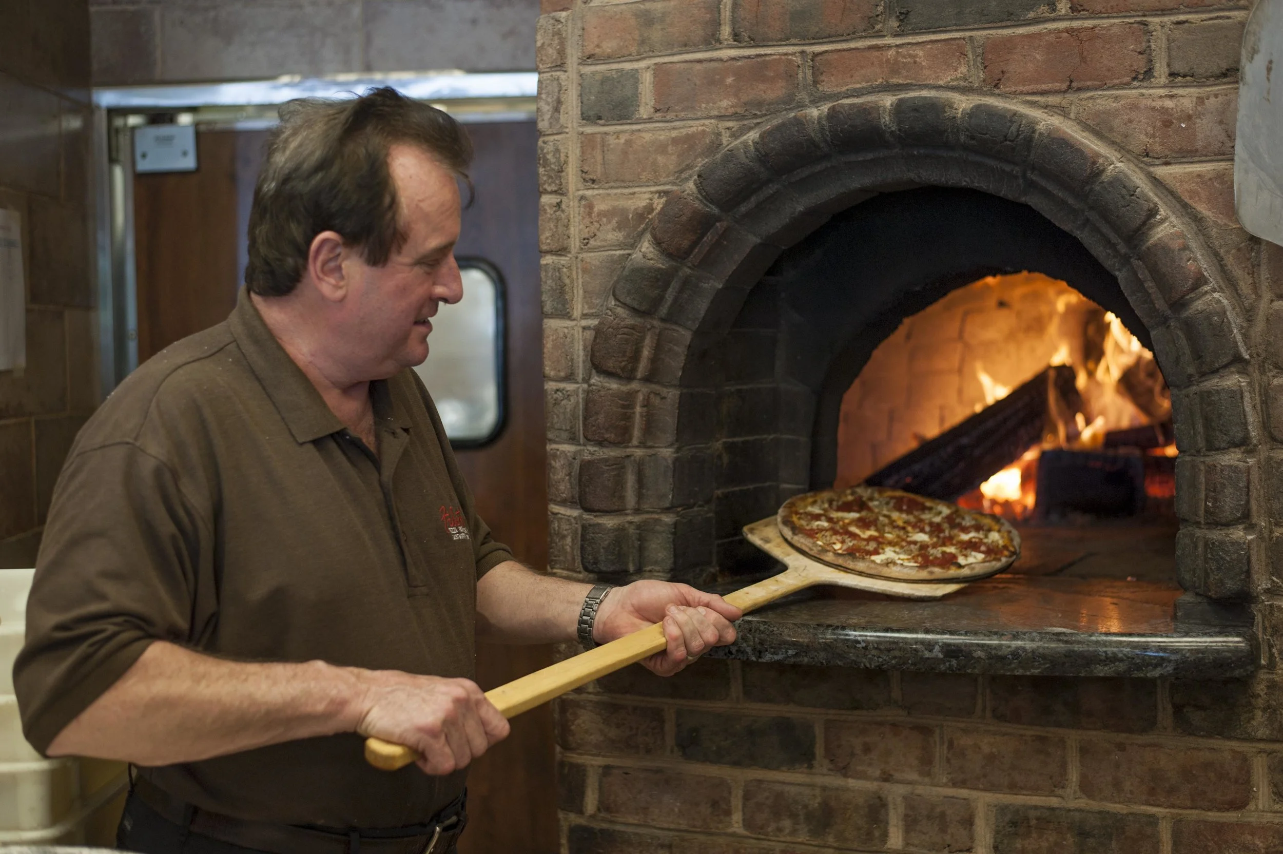   Long Islander News photos/David Weber  Rich Braue, co-owner of Filetto’s ristorante and head chef with more than 40 years of culinary expertise, puts in a pizza into the establishment’s renowned brick oven. 