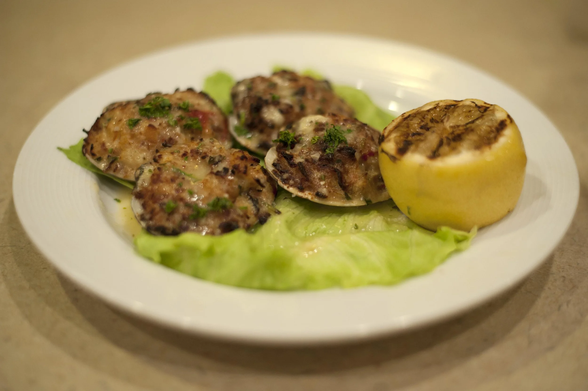  The Stuffed Baked Clams plates fresh chopped clams, bacon, onions, peppers topped with a light scampi sauce and served with a grilled lemon for added zestiness. 