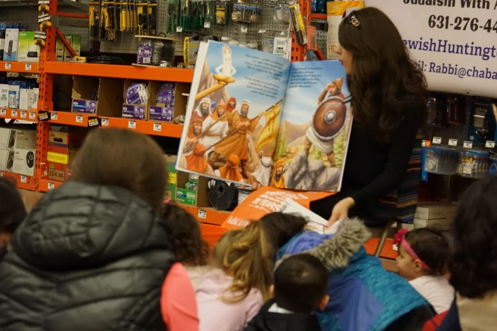   Children listen in during Jewish story time with Chaya Raskin, who read from a two-foot Chanukah book.&nbsp;  Photo Courtesy of Chabad of Huntington Village  