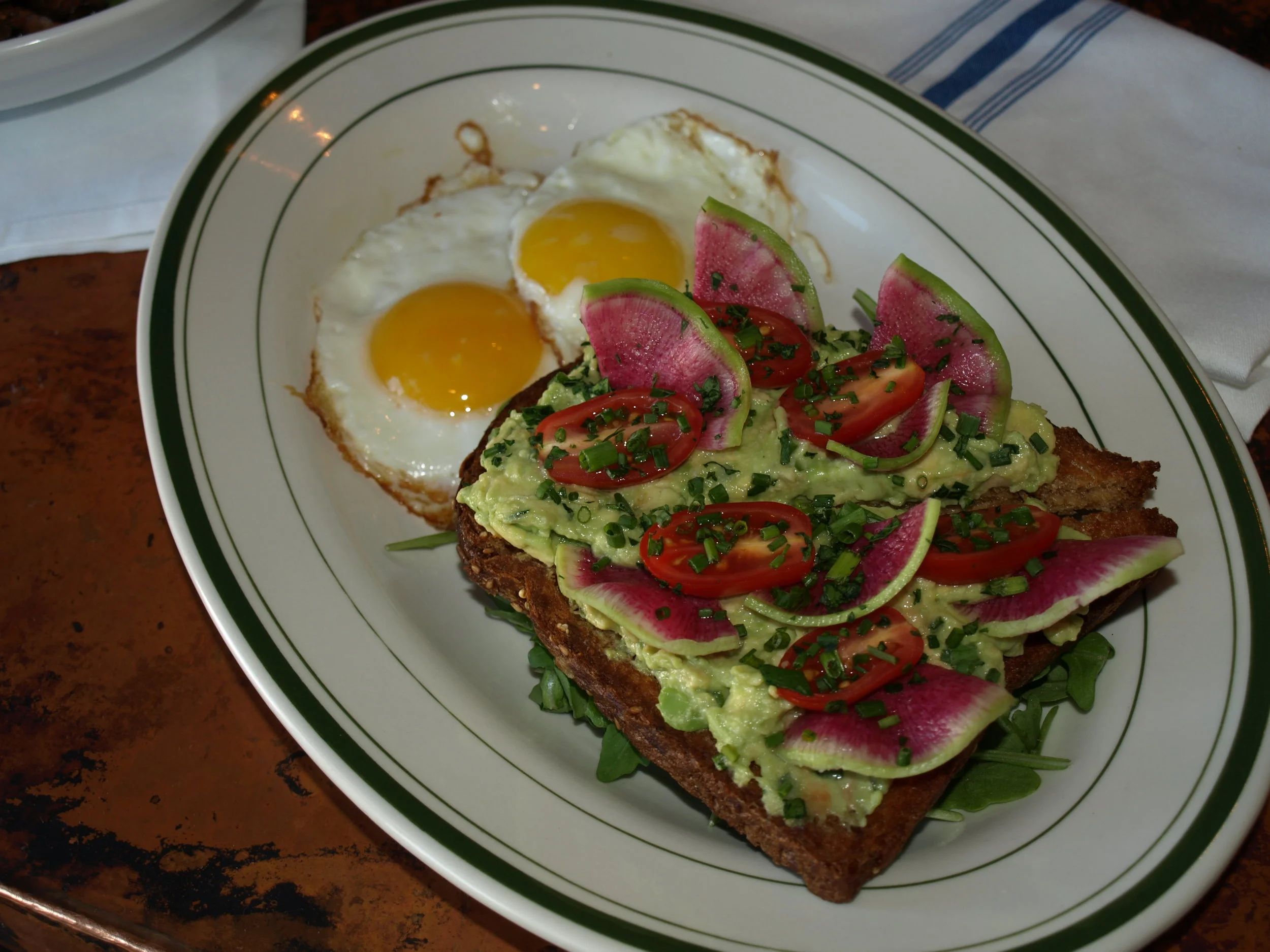   The Avocado Toast and Sunny Eggs ($13) is served with watermelon radish, tomato, arugula and two sunny side eggs .  Long Islander News photos/Connor Beach  
