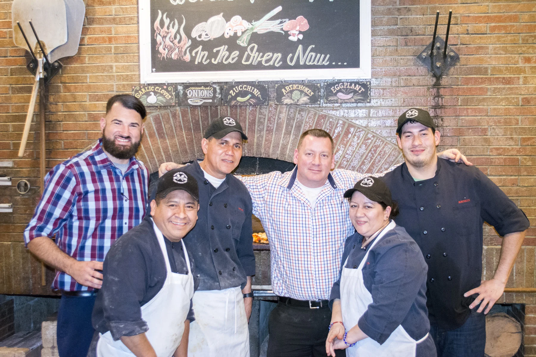   General Manager Corey Grossman, third from right, and the staff in front of the pizza oven at Bertucci’s in Melville.   Long Islander News photos/Connor Beach  