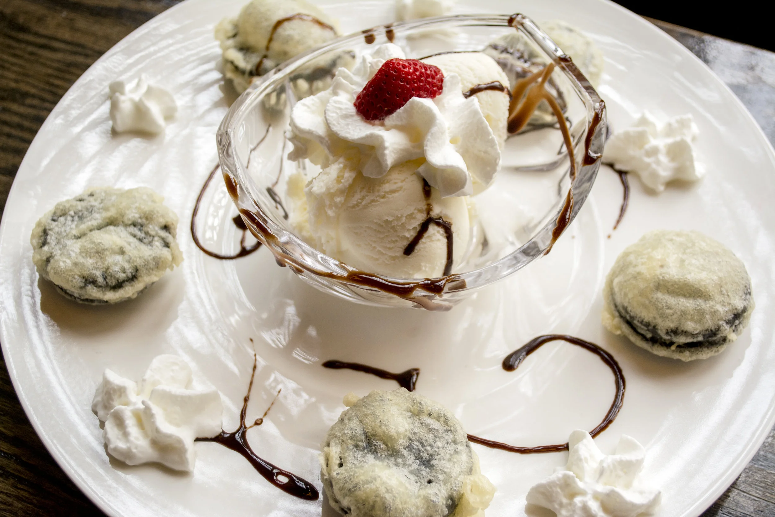   Tempura Fried Oreos are topped with whipped cream and served with a bowl of vanilla iced cream.  