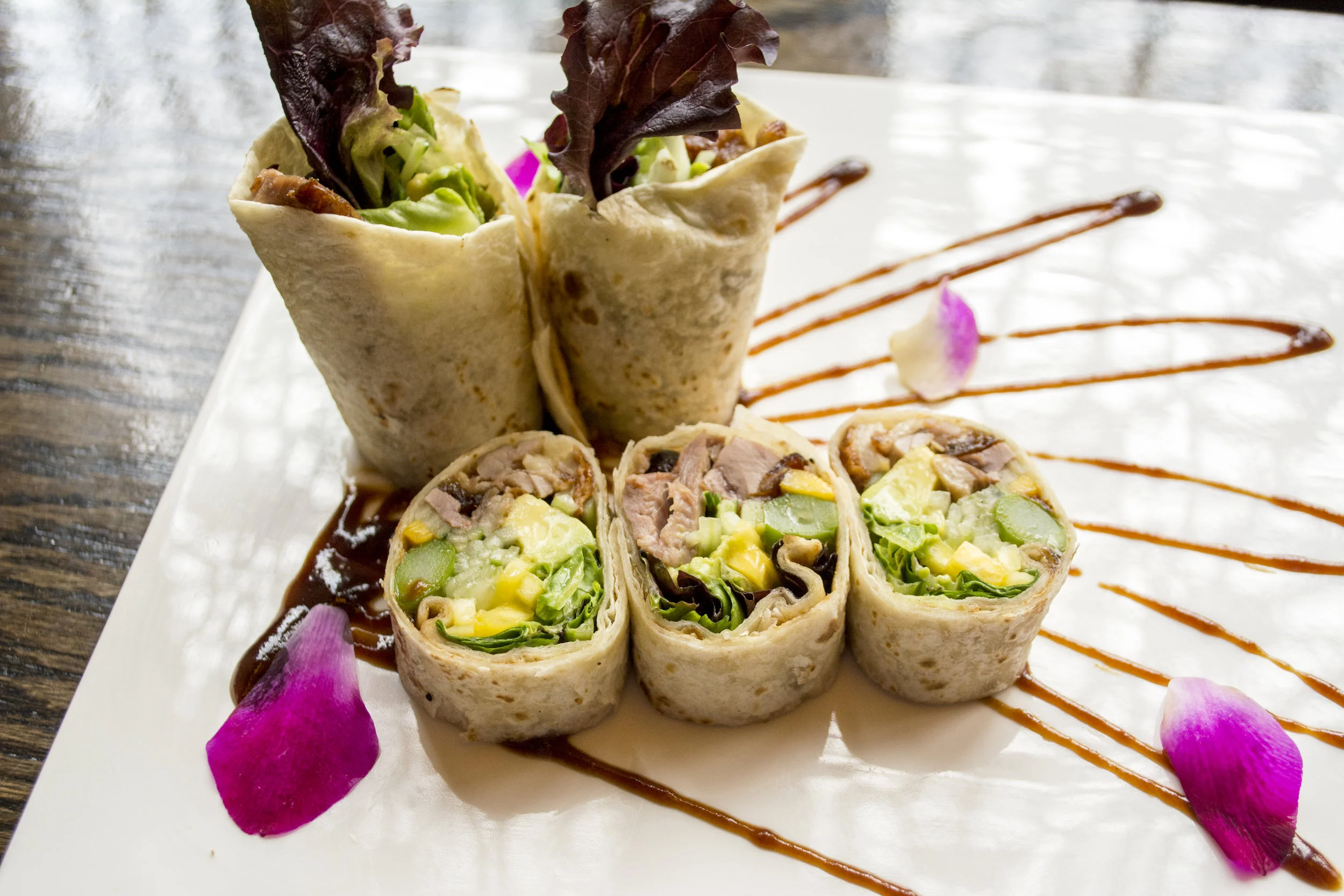   Duck Tacos include duck breast, mixed greens, avocado and cucumber wrapped in a tortilla with a honey mustard and hoisin sauce.  