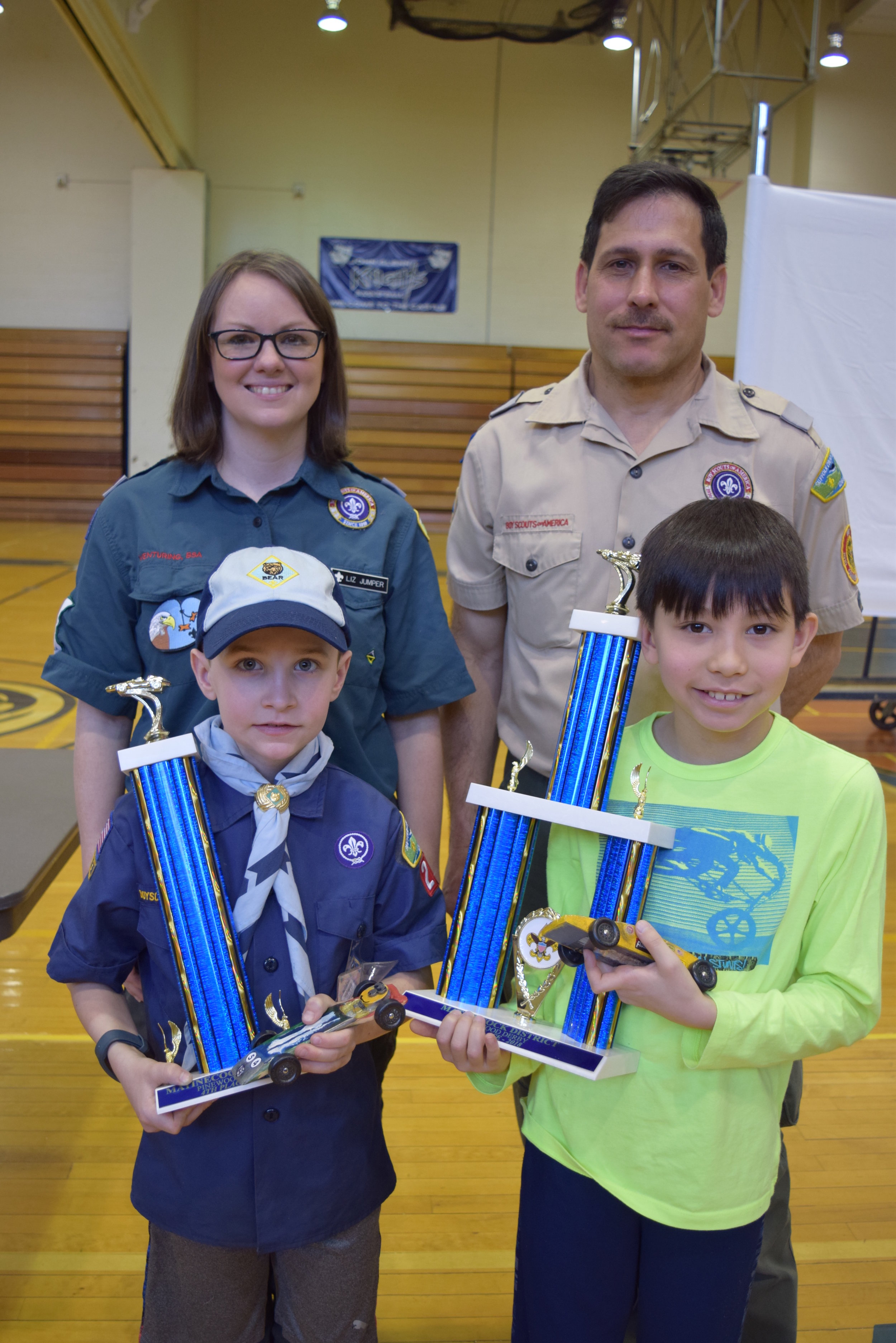   Jack R., front-left, and Evan A., front-right, of Greenlawn’s Pack 225 placed fourth and third respectively in last weekend’s races. They’re pictured with their trophies and hand-crafted pinewood derby racecars.  
