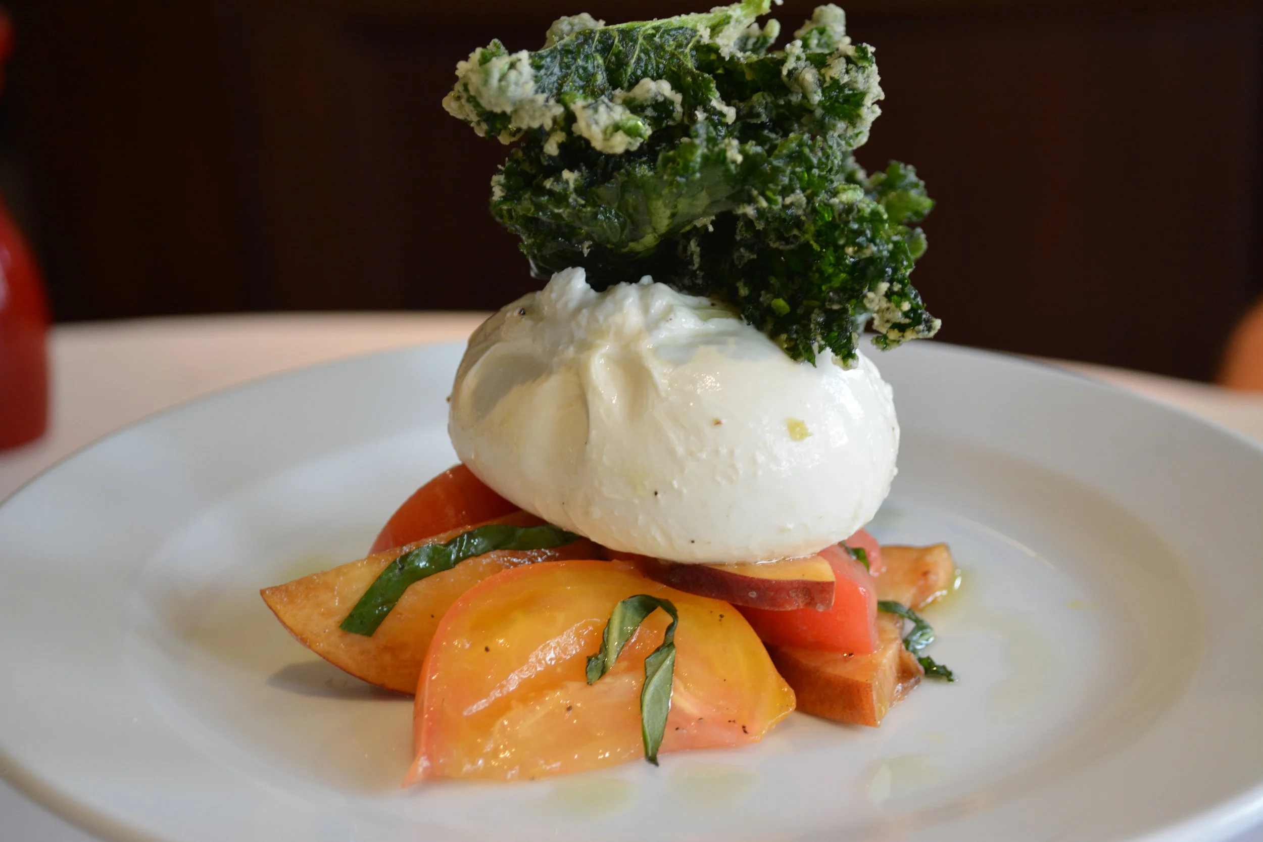   Rich, creamy Burrata ($15) with peach, heirloom tomato and crispy kale.  