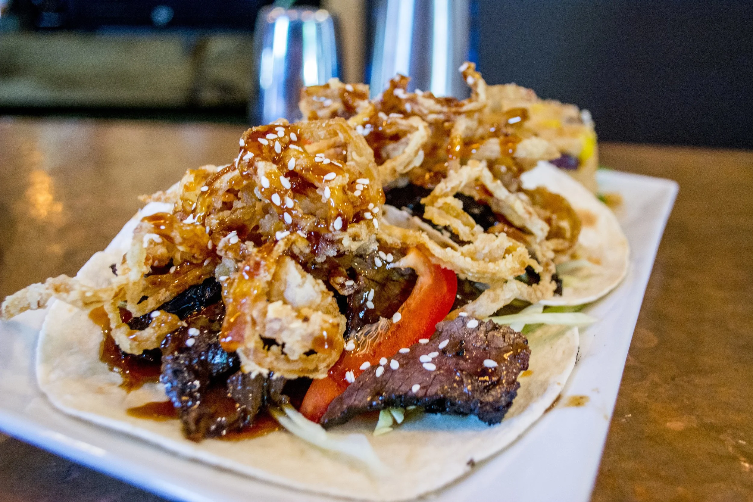   Asian Steak Tacos ($9) with shredded cabbage, bell peppers, fried onions, teriyaki sauce and sesame seeds.  