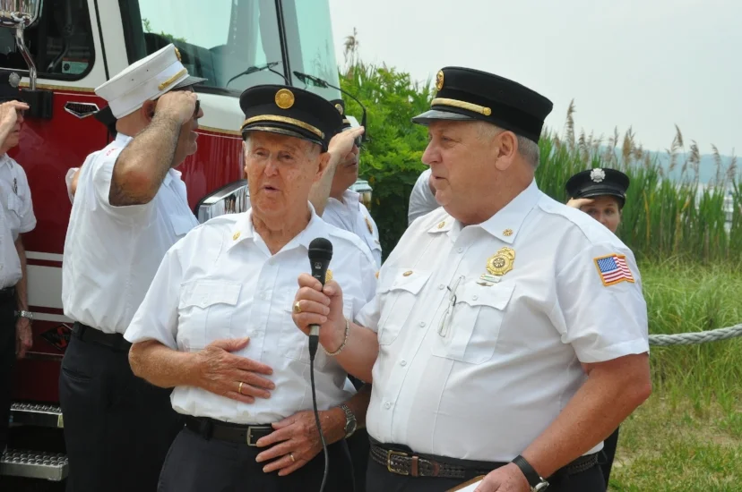   Eaton’s Neck firefighter, former fire commissioner and World War II veteran Roy Beach, left, leads the salute to the flag. He turned 92-years-old on July 4.  