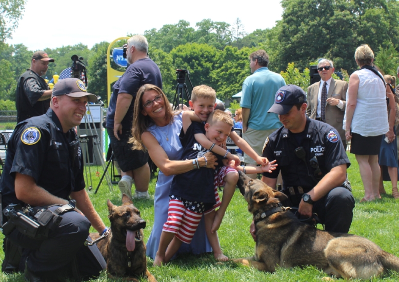   Lisa Tuozzolo and sons Austin and Joseph with officers Schondebare, left, and Bosco, right, of the MTA Police Department Police Canine Unit and their canine officers, Zolo, left-center, and Tuz, right-center.  