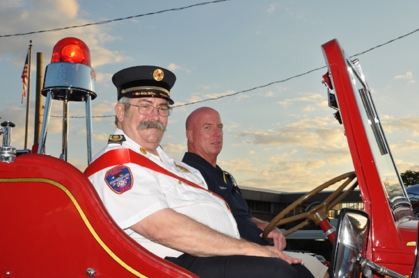   This year’s parade grand marshal was Huntington Manor ex-Chief Steve Lygren, left, who has 31 years of service. He rides in the department’s antique truck with firefighter Tommy O’Donnell, right.   (Photos by Steve Silverman)  